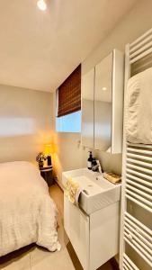 a white bedroom with a bed and a sink at Seanest - North Sea Stays in De Haan