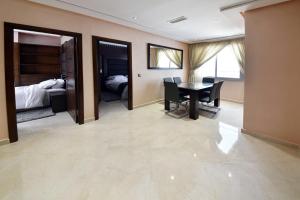 a dining room with a table and a bedroom at Bellington Appart Hôtel in Saïdia