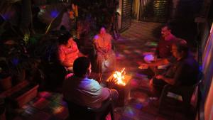 eine Gruppe von Menschen sitzt um ein Feuer in einem Raum in der Unterkunft Coorg peacock feathers home stay in Kushālnagar