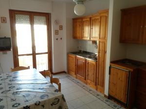 a kitchen with wooden cabinets and a table with a tablecloth at Holiday House in Alghero