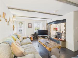 een woonkamer met een bank en een tafel bij Cosy Cornish Cottage with Firepit & Parking in Newlyn East