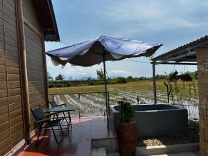 a patio with an umbrella and a table and chairs at The Rustic Tree Farm in Thôn An Thạnh