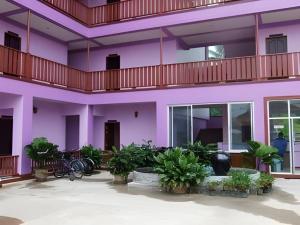 un bâtiment violet avec des plantes dans une cour dans l'établissement Erawan Place, à Mae Sot