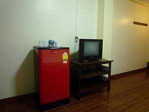 un réfrigérateur rouge à côté d'une table avec une télévision dans l'établissement Erawan Place, à Mae Sot