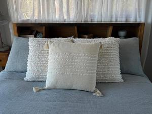 eine Gruppe von Kissen auf einem Bett in der Unterkunft Waterfront - Bluff Beach House, Park Beach in Dodges Ferry
