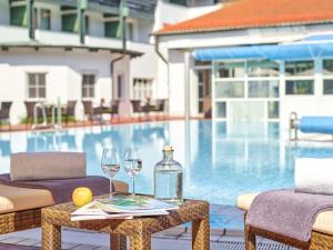 a table with wine glasses and a bottle next to a swimming pool at Fit Vital Aktiv Hotel DAS LUDWIG in Bad Griesbach