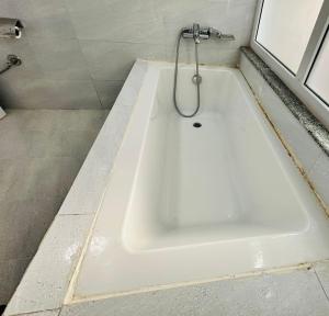 een wit bad met een douche in de badkamer bij Prem Durbar Hotel in Changunarayan +17 foto's