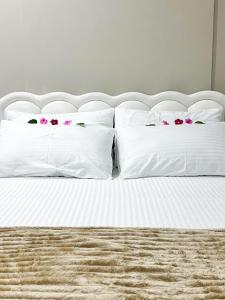 un lit blanc avec des fleurs roses sur les oreillers dans l'établissement Sosun View Private Villa, à Thoddoo