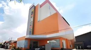 - un grand bâtiment avec des tons orange et blanc dans l'établissement Sakura Manado, à Manado