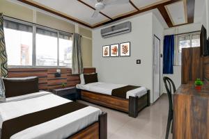 ein Hotelzimmer mit zwei Betten, einem Tisch und einem Fenster in der Unterkunft Hotel O Galaxy Inn in Ballygunge