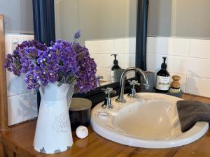 eine Vase lila Blumen neben einem Waschbecken in der Unterkunft Waterfront - Bluff Beach House, Park Beach in Dodges Ferry