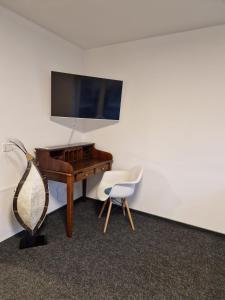 a room with a piano and a chair and a television at Modernes Apartment in Huttenberg