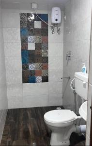 a bathroom with a toilet and a tile wall at Costa Rica in Kumta