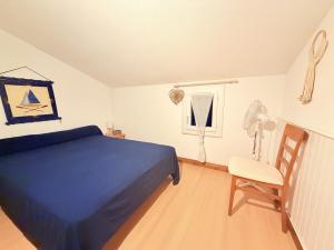 a bedroom with a blue bed and a chair at Les Sables in Saint-Georges-dʼOléron