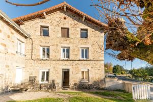 een oud stenen huis met een groot raam bij Studio Chambre St Genest Malifaux in Saint-Genest-Malifaux