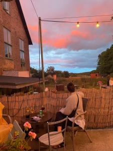 a woman sitting at a table on a patio at Stuga i Maglehem in Degeberga