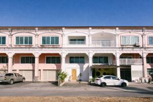 un bâtiment rose avec deux voitures garées devant lui dans l'établissement PANI Place Khaolak, à Khao Lak