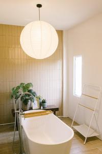 une salle de bains avec une baignoire blanche et un luminaire dans l'établissement PANI Place Khaolak, à Khao Lak