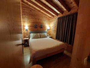 een slaapkamer met een bed in een houten kamer bij Bungalows Nou Camping in Guingueta