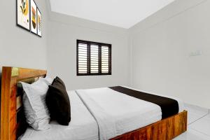 une chambre avec un lit avec des draps blancs et des oreillers dans l'établissement Hotel O THAIBA RESIDENCY, à Kuttyādi