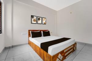 un lit dans une chambre blanche avec deux tableaux sur le mur dans l'établissement Hotel O THAIBA RESIDENCY, à Kuttyādi