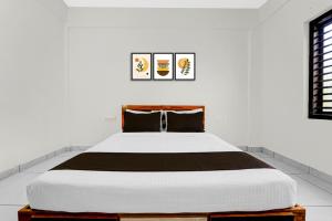 - une chambre blanche avec un grand lit et des oreillers noirs dans l'établissement Hotel O THAIBA RESIDENCY, à Kuttyādi