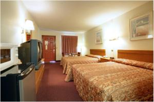 a hotel room with three beds and a flat screen tv at Americas Best Value Inn Cartersville in Cartersville