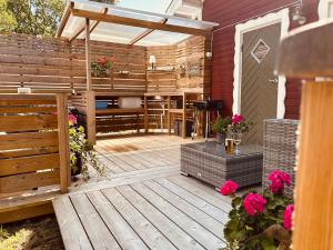 a patio with a wooden deck with flowers at Kaj's Cabin in Listerby