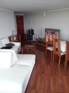 a living room with white furniture and a dining room at Vista Laguna in San Pedro de la Paz