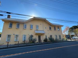 a large yellow house on the side of a street at hayama satoyado in Hayama
