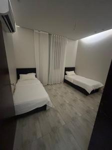 two beds in a room with white walls and tile floors at شاليهات ايفا 2 in Taif