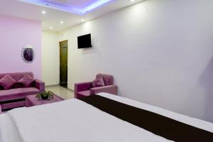 ein Schlafzimmer mit einem Bett und zwei lila Stühlen in der Unterkunft Hotel O Royal Sangrila Inn in Dānāpur