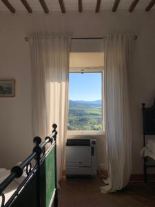 ein Schlafzimmer mit Fenster und einem Bett mit Fernseher in der Unterkunft Casa Cerboneschi B&B in a medieval village with Panoramic Tuscan Hills in Casale Marittimo