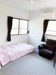 una camera da letto con un letto e una sedia di The Village House 1 a Hadano