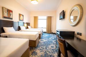 ein Hotelzimmer mit 3 Betten und einem Spiegel in der Unterkunft Al Hidayah Towers Hotel in Mekka