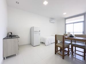 eine weiße Küche mit einem Tisch und einem Kühlschrank in der Unterkunft Moderno con vistas al Río in Pueblo Esther + 7 Fotos