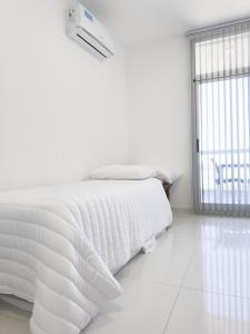 ein weißes Bett in einem weißen Zimmer mit Fenster in der Unterkunft Moderno con vistas al Río in Pueblo Esther