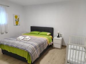 a bedroom with a bed with green sheets and a crib at My Flowers in Árgos Orestikón