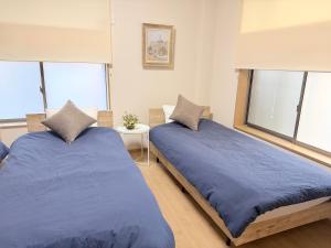 2 Betten nebeneinander in einem Zimmer mit Fenstern in der Unterkunft MY HOUSE たいみんぐ kuwana 長島15分 名古屋20分 桑名駅徒歩3分 in Kuwana + 41 Fotos