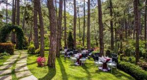 un jardin avec des tables et des chaises dans l'herbe dans l'établissement Le Monet Hotel, à Camp John Hay