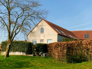 a white house with a red roof and a hedge at Kraaiberg in Ploegsteert