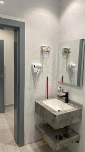 een badkamer met een stenen wastafel en een spiegel bij نسيم الربيع 2 للشقق المخدومة in Quai +14 foto's