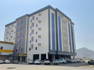 een groot gebouw met auto's geparkeerd op een parkeerplaats bij نسيم الربيع 2 للشقق المخدومة in Quai