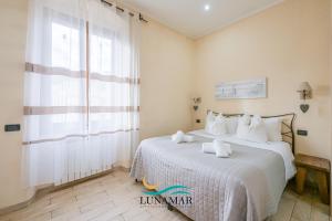 a bedroom with a bed with white sheets and a window at Affittacamere Lunamar in La Spezia