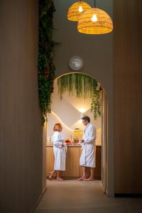 two people standing in a kitchen preparing food at Hotel Delfin in Izola +42 photos