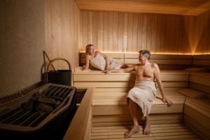 a man and a woman sitting in a sauna at Hotel Delfin in Izola