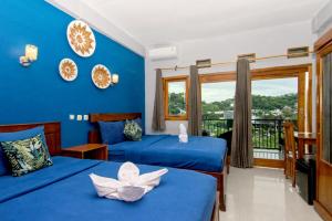 a bedroom with two beds and a blue wall at Hotel Bonne Nuit in Labuan Bajo