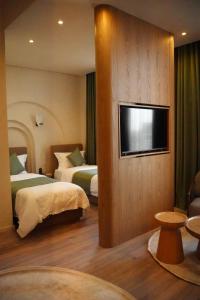 ein Hotelzimmer mit zwei Betten und einem Flachbildfernseher in der Unterkunft Dastan Grand Hotel in Jalal-Abad