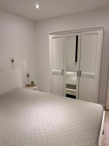 a white bedroom with a bed and a cabinet at Bungalow kleine Deichperle, Strand, Deich und ein wunderschöner kleiner Ort in unmittelbarer, fußläufger Nähe! in Lemmer +33 photos