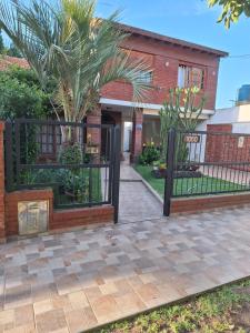 a gate in front of a house with palm trees at departamentos 4 personas,N3 Aire acondicionado Wifi TvCable Parrilla in Santa Teresita +2 photos